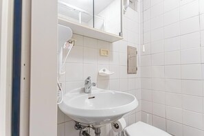 A bathroom with a white sink, a mirror, and a toilet.