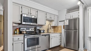 Una cocina moderna con electrodomésticos de acero inoxidable, armarios blancos y un salpicadero de azulejos.