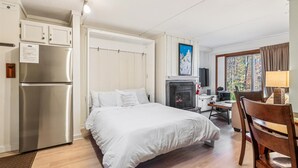 Un dormitorio con cama, televisión integrada, chimenea y escritorio con silla.