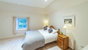 A bedroom with a bed, bedside table, lamp, and a framed picture on the wall. - Penninghame Estate - Bruce Apartment (Penninghame)