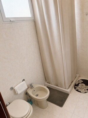Une salle de bain équipée de toilettes, d’un bidet et d’un rideau de douche.