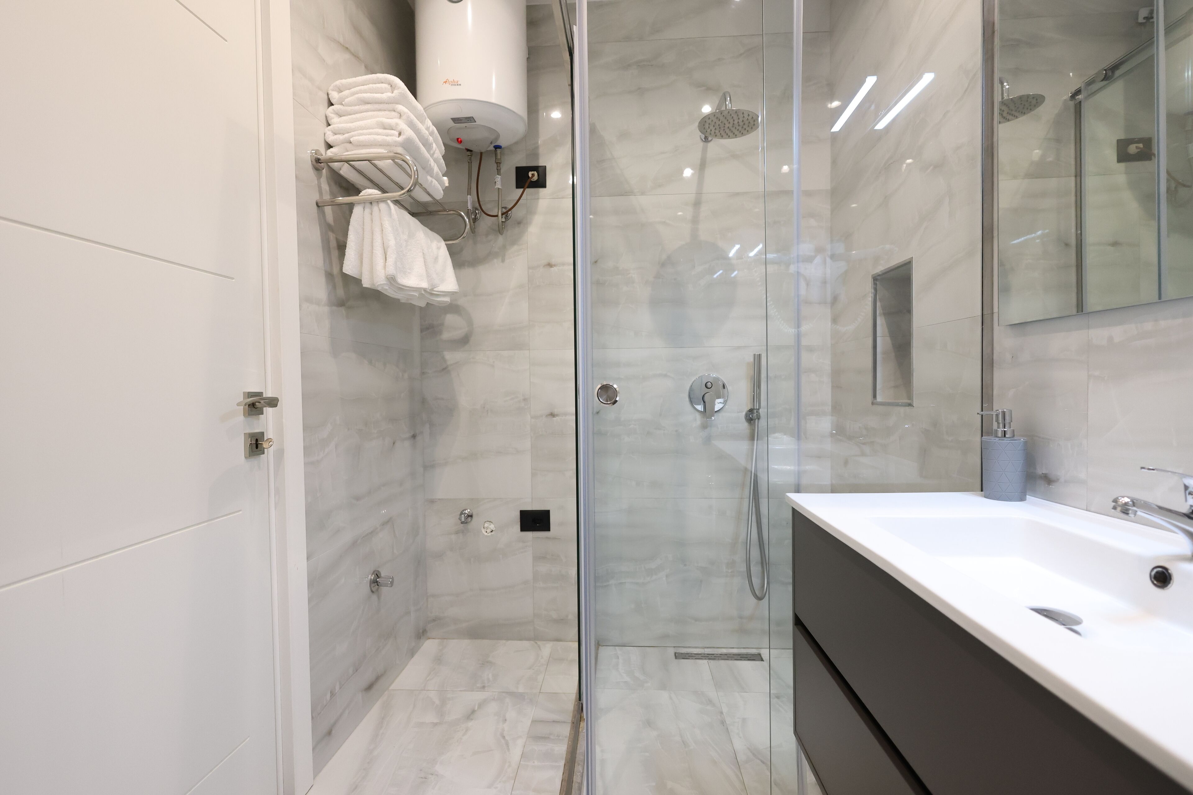 Une salle de bain moderne avec une douche à parois de verre, un lavabo blanc et un porte-serviettes.
