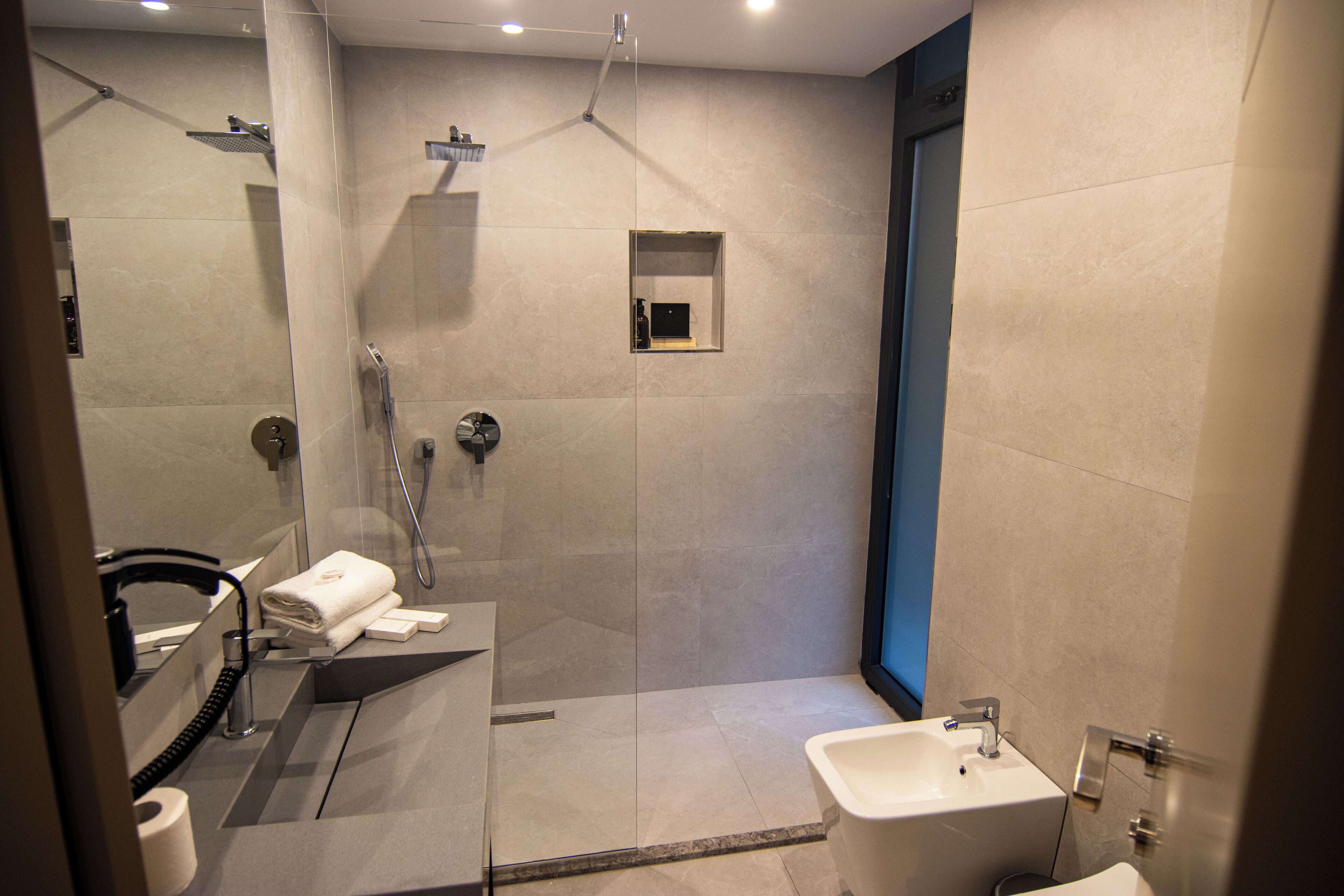 A modern bathroom with a glass-enclosed shower, a sink, and a mirror.