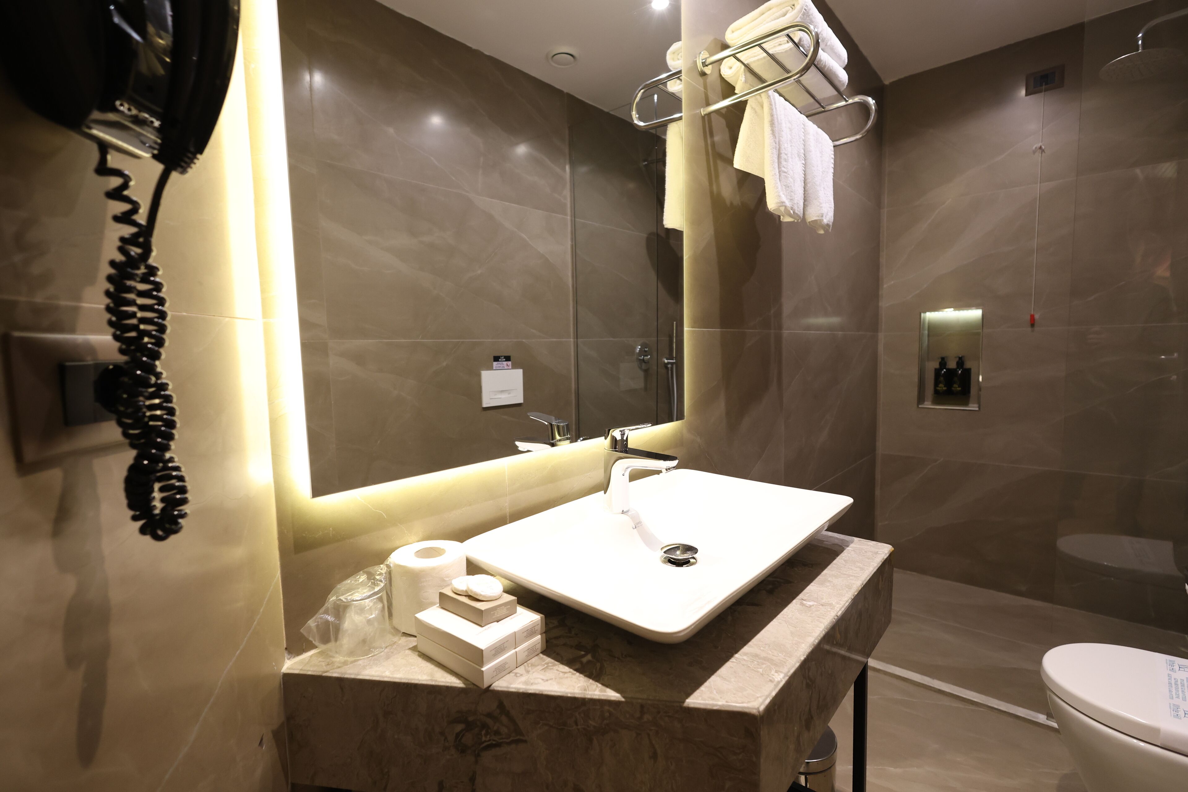 Une salle de bain moderne avec un grand miroir, un lavabo et une douche.