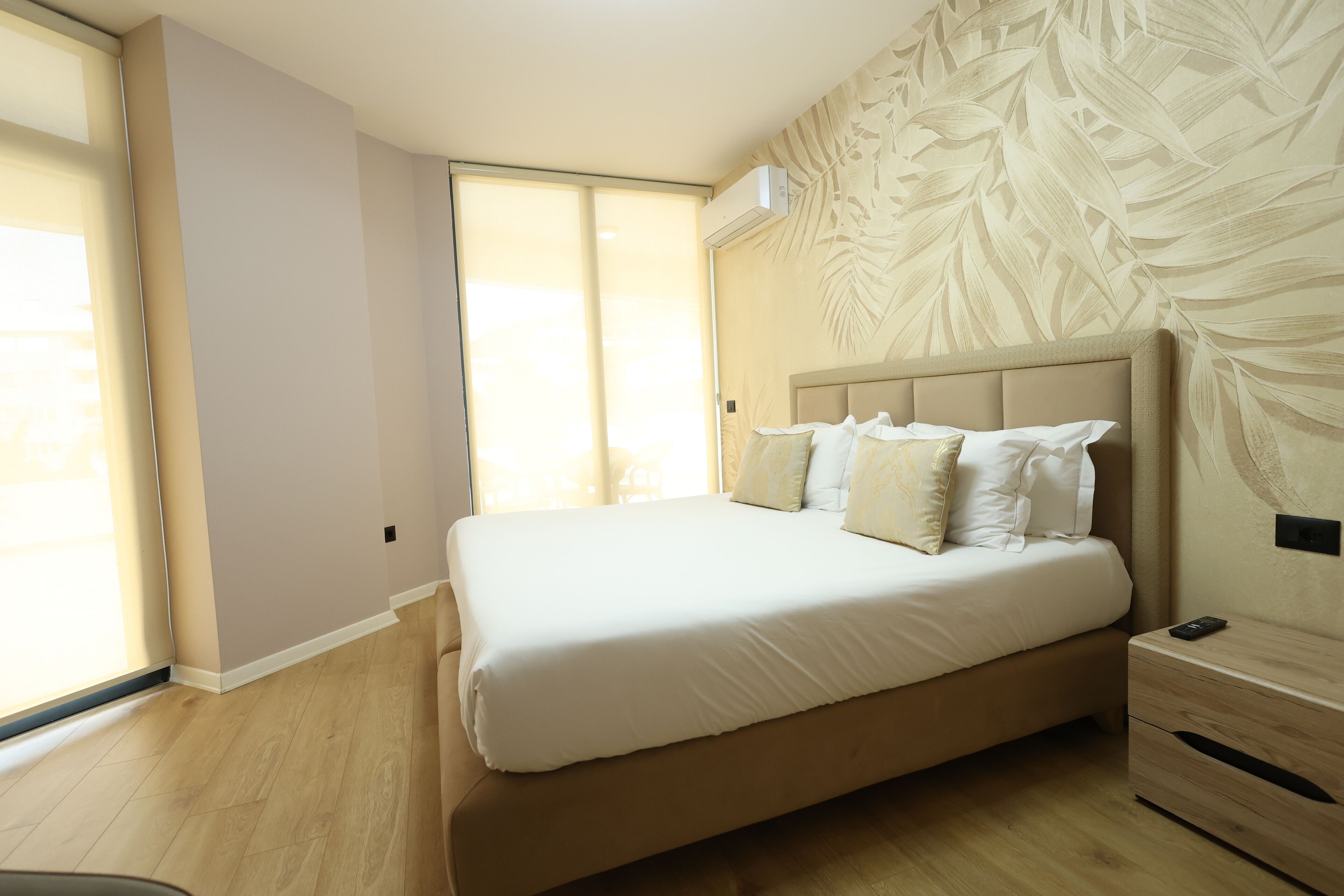 A bedroom with a large bed, a nightstand, and a wall-mounted air conditioner.