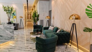 A modern lobby with a green sofa, floor lamps, and marble flooring. - White Hill Hotel Spa & Conference (Durres)
