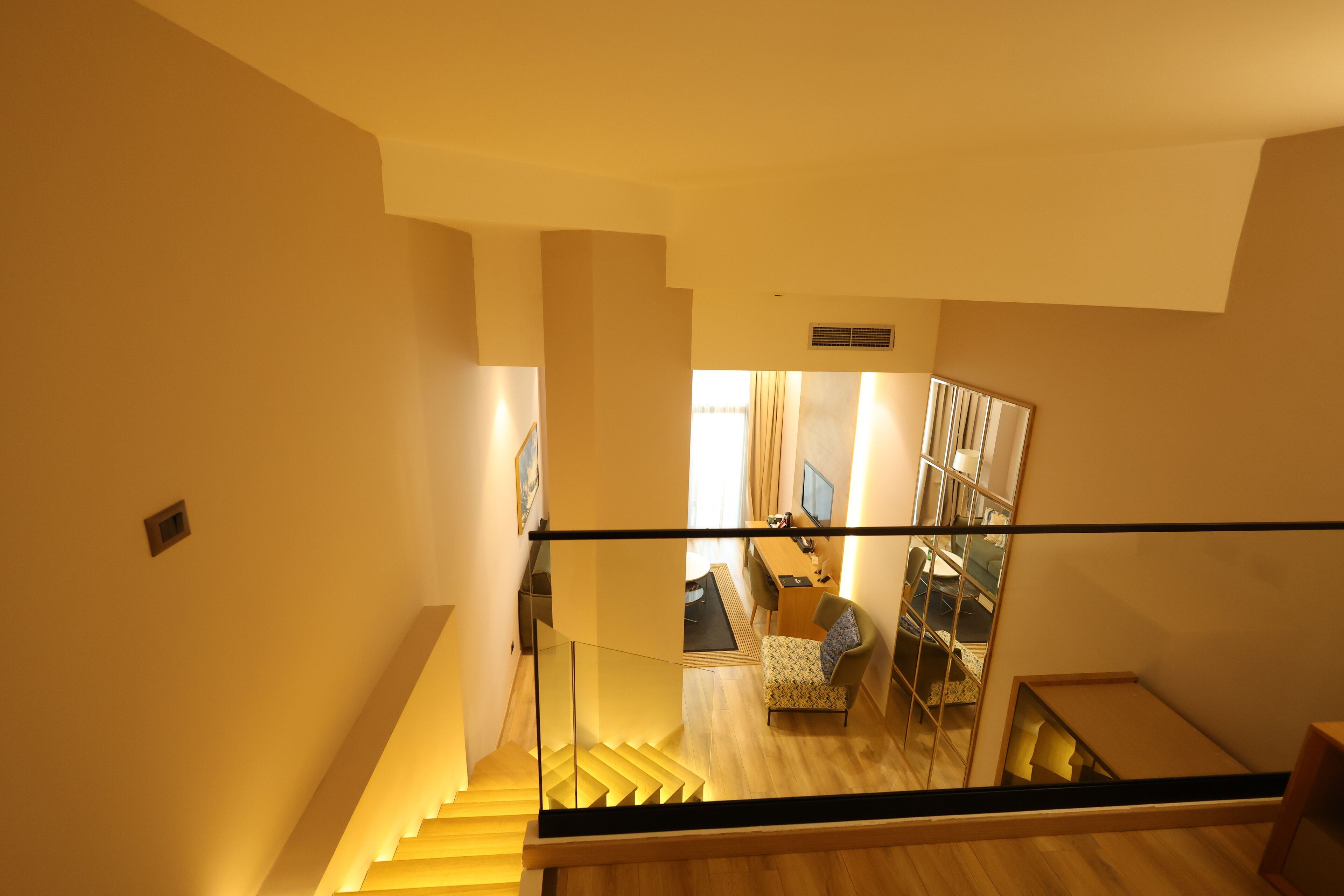 A staircase leading to a living area with a sofa, a chair, and a desk.