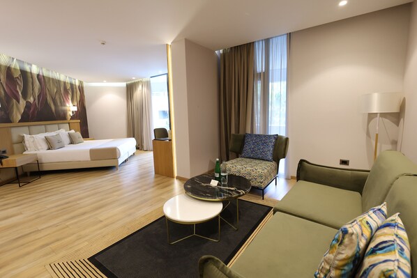 Ein Hotelzimmer mit Bett, einer Couch, einem kleinen Tisch, einem Sessel und einem großen Gemälde an der Wand.