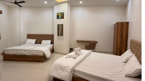 A modern hotel room with two beds, a ceiling fan, recessed lighting, and a wooden cabinet. - Hotel Lake Heart  (Udaipur)