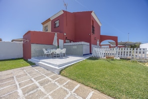 A red house with a patio, white fence, and a small lawn.