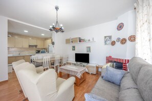 Un salon avec un canapé, des fauteuils, un téléviseur et une cheminée.