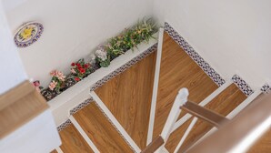 Eine Holztreppe mit weißen Geländern, einer verzierten Bordüre und einer Blumenkomposition an der Wand.