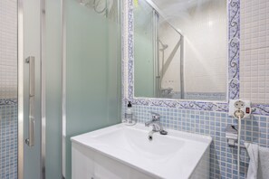 A bathroom with a white sink, a mirror, and a shower enclosure.
