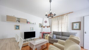 Ein Wohnzimmer mit einer Couch, einem Fernseher, einem Holzesstisch und einem Kamin.
