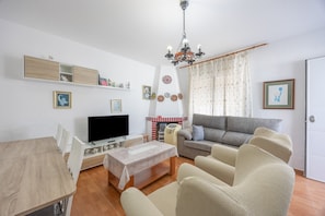 A living room with a sofa, TV, wooden dining table, and a fireplace.