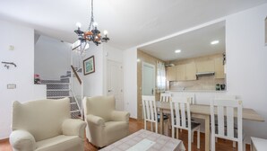 Ein Wohnzimmer mit Sofa, Sesseln, einem Esstisch und einer Kristallleuchtre.
