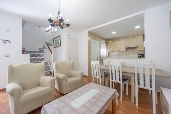 Un salon comprenant un canapé, des fauteuils, une table à manger et un lustre.