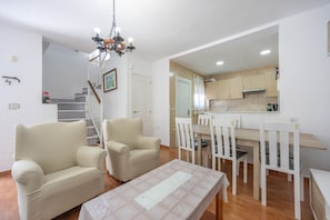 A living room with a sofa, chairs, a dining table, and a chandelier.