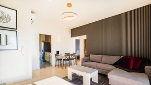 Un salon moderne comprenant un canapé, une table basse et un coin repas avec des chaises et une table.