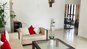 Amplia sala de estar con un conjunto de sofás, una mesa de centro y un comedor al fondo.