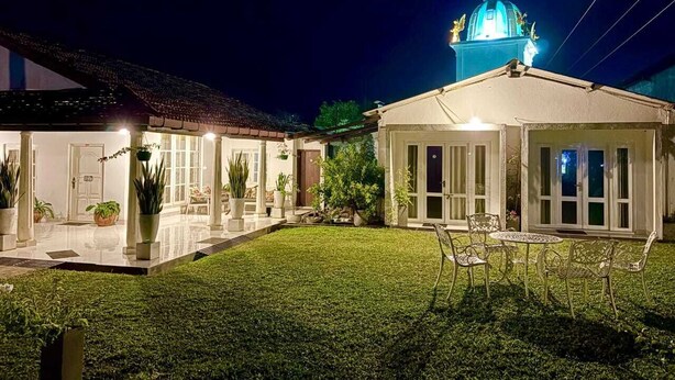 Una propiedad residencial bien iluminada con un patio amplio, piscina y un edificio grande de cúpula azul al fondo.