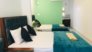 Una habitación de hotel con una cama, dos mesitas de noche, una silla y una pequeña cocina.