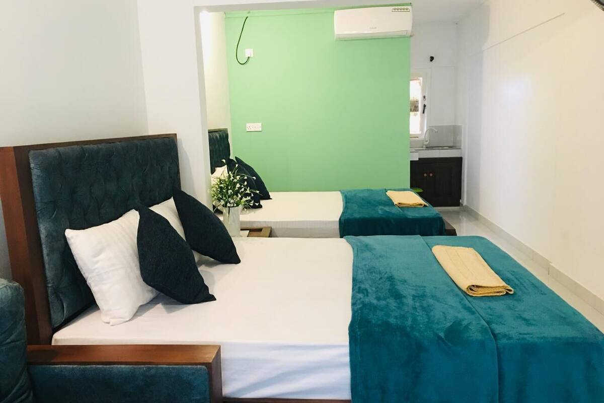 A hotel room with a bed, two bedside tables, a chair, and a small kitchenette.