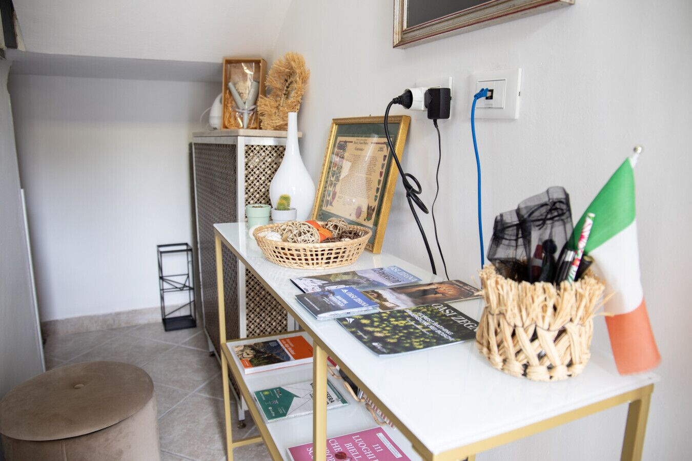 En välordnad arbetsplats med ett skrivbord, böcker, en korg och en liten krukväxt.