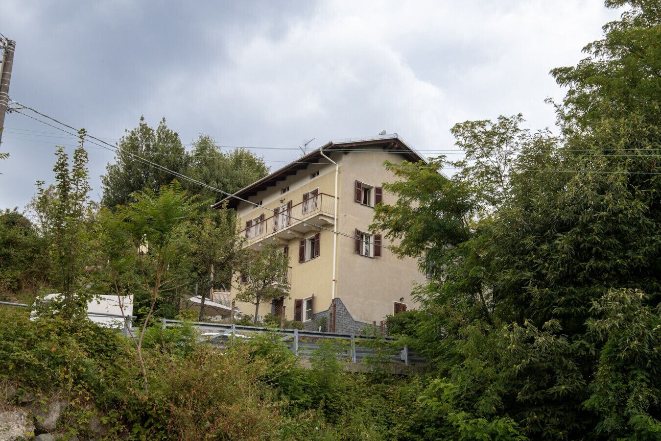 Un edificio de varios pisos con balcones, rodeado de abundante vegetación.