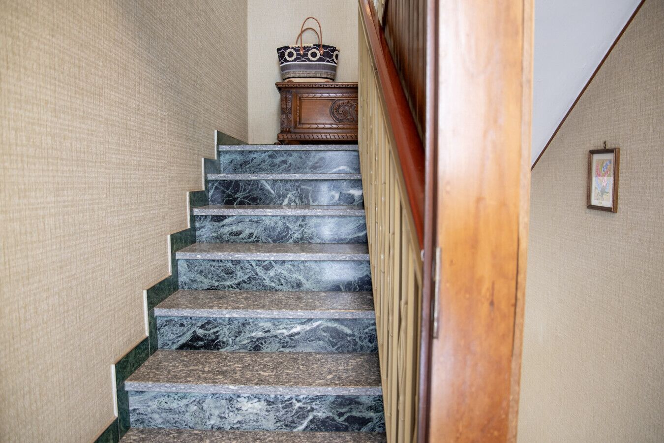 Uma escadaria de mármore com corrimão de madeira e um objeto decorativo no último degrau.