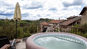 Un jacuzzi sur un balcon avec vue sur les maisons et les arbres.