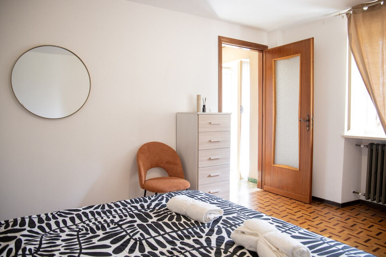 Ein Schlafzimmer mit Bett, Stuhl, Kommode und Spiegel.