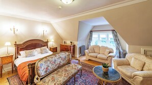 A bedroom with a bed, two sofas, a small table, and a window with curtains.