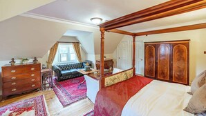 A spacious bedroom with a four-poster bed, a dresser, a sofa, and a large wardrobe. - Penninghame Estate - Tower Apartment (Penninghame)