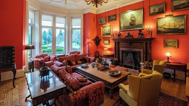 A room with a fireplace, red walls, and large windows.