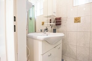 A modern bathroom with a white sink, mirror, and tiled walls.
