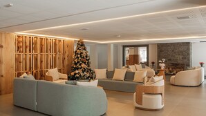 A modern living room with a large Christmas tree, sofas, and a fireplace. - Harmont Hotel (Gramado)