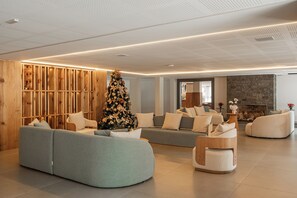 A modern living room with a large Christmas tree, sofas, and a fireplace. - Harmont Hotel (Gramado)