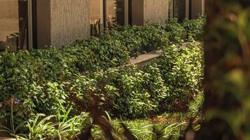 Um edifício com grandes janelas e um jardim bem cuidado, com diversas plantas.