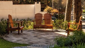 A patio with two wooden Adirondack chairs and a bench, surrounded by a low wall and greenery. - Harmont Hotel (Gramado)