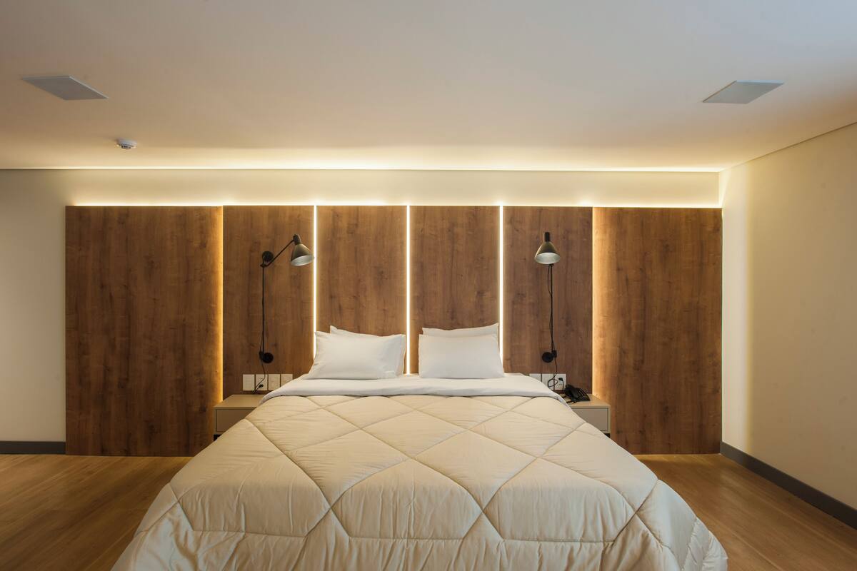 A modern bedroom with a large bed, wooden panel wall, and bedside lamps.