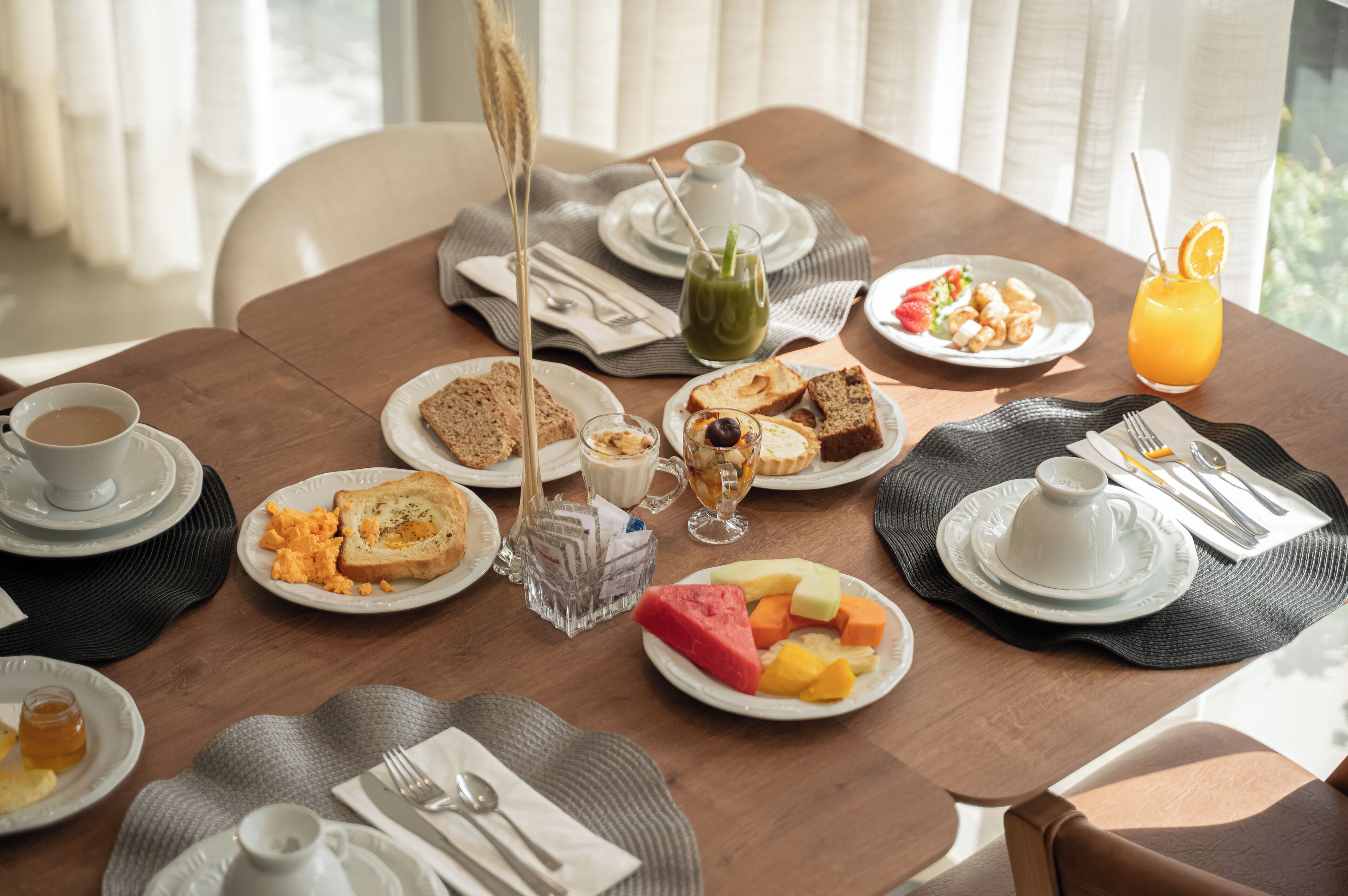 A dining table set with breakfast items including toast, scrambled eggs, and fruit.