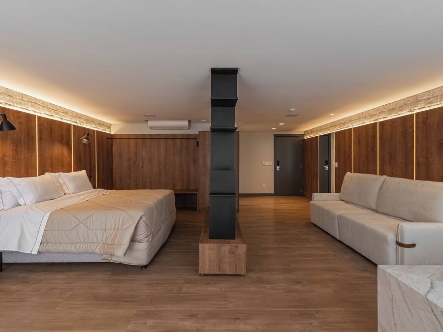 Quarto moderno com uma cama grande, um sofá e um luminário vertical exclusivo.
