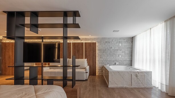 A modern bedroom with a large bed, a sofa, a TV, a wooden wardrobe, and a marble bathtub. - Harmont Hotel (Gramado)