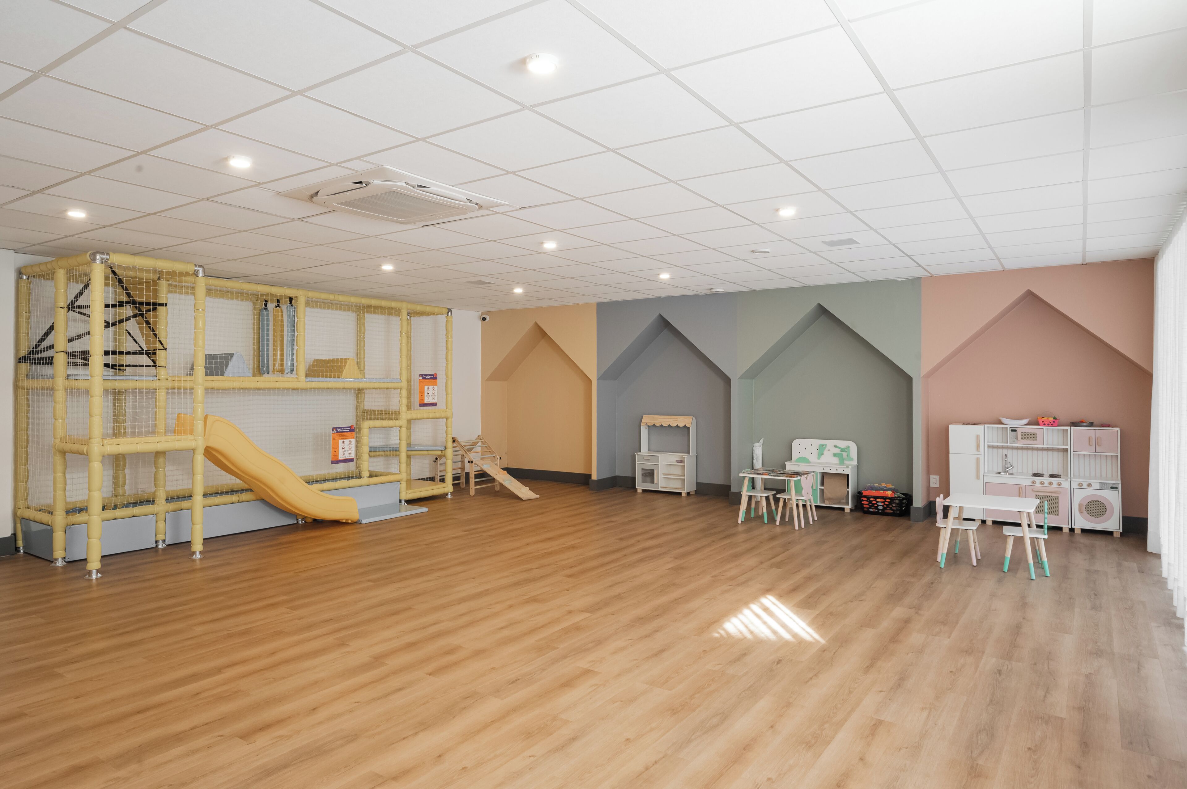 Ein Spielzimmer mit Rutsche, Spielbereich und Kinderzimmermöbeln.
