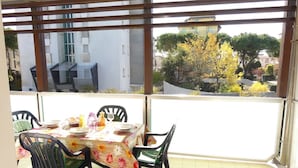 A balcony with a table set for four, chairs, and a view of buildings and trees.