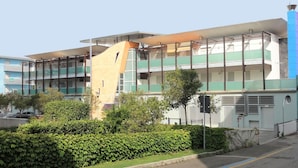 Un edificio de varios pisos con un diseño arquitectónico moderno, que cuenta con balcones y grandes ventanales.