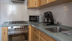 A kitchen with a gas stove, microwave, coffee maker, and a sink. - AS HOME Nożownicza (Wrocław)
