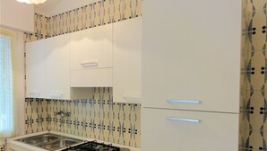 A kitchen with white cabinets, a gas stove, and a patterned backsplash. - Apartment in villa with fenced garden (Bibione)