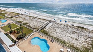Ein Strandhotel mit Schwimmbad, Strandliegen und einer Promenade.